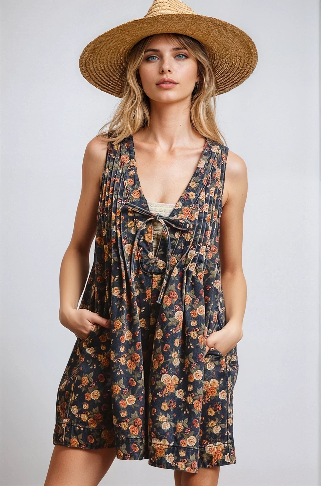 Woman wearing a floral dress and straw hat against a plain background