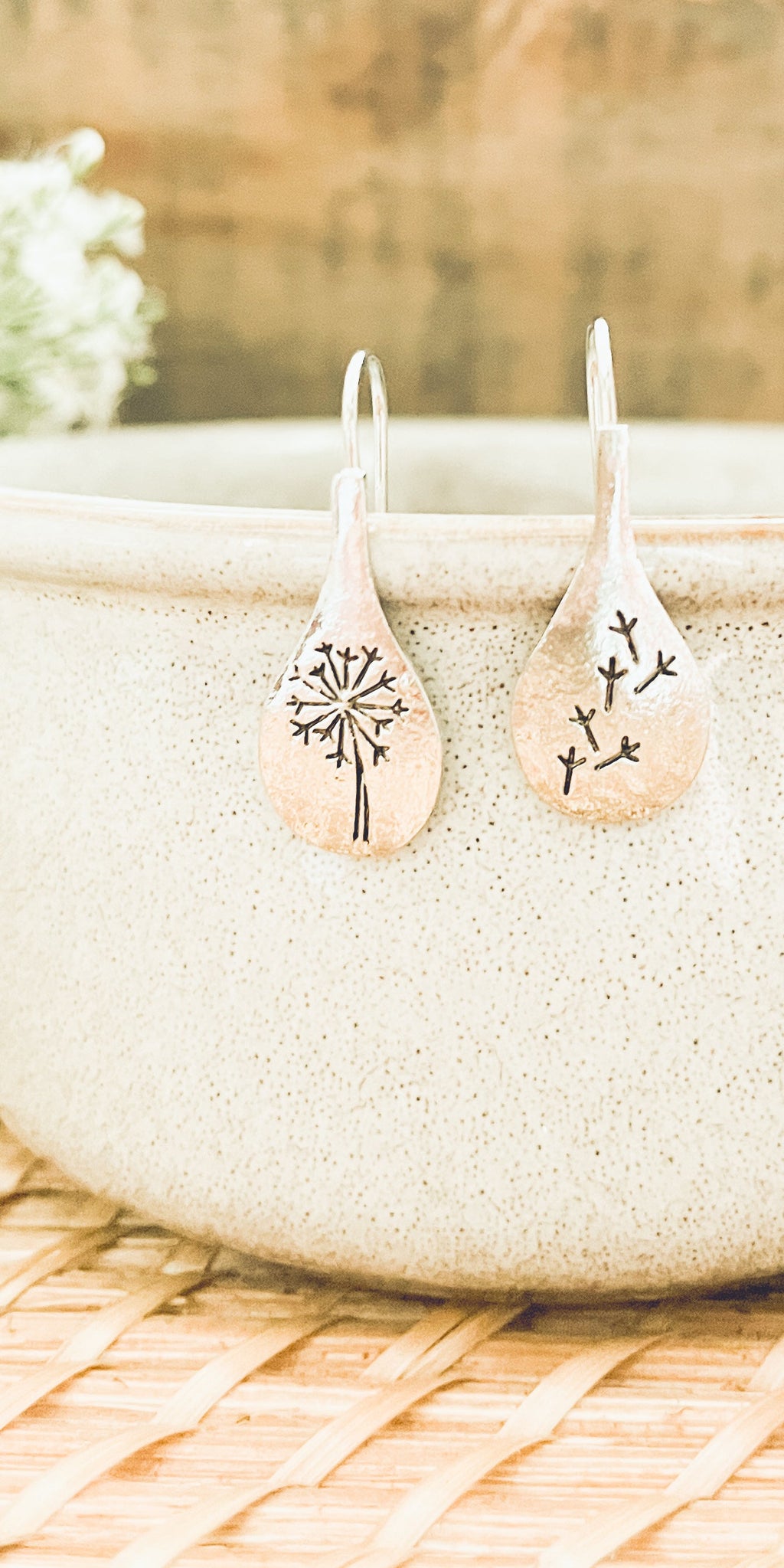 Pair of earrings with floral designs on a stone surface