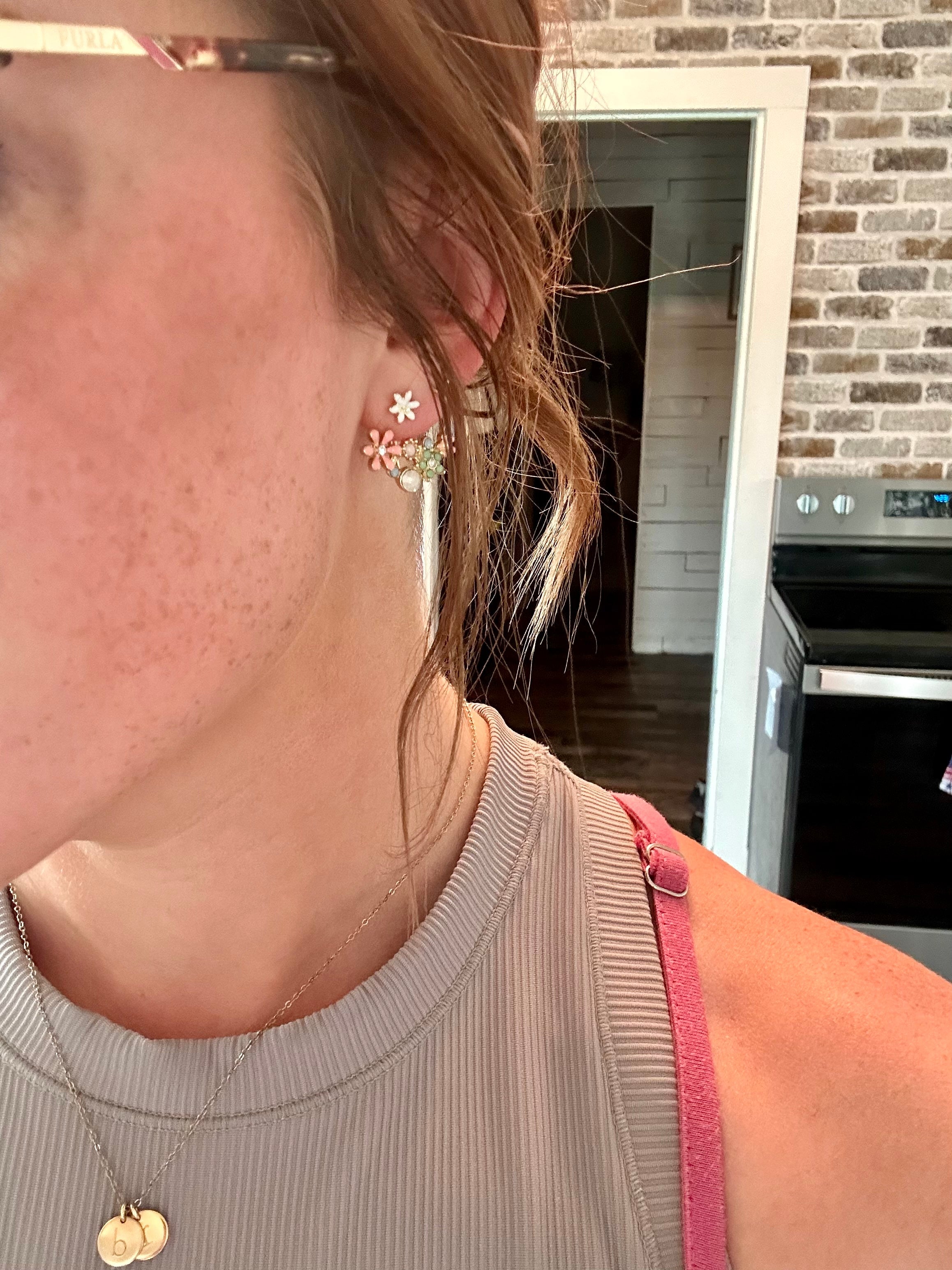 Close-up of a person wearing floral earrings with a kitchen background