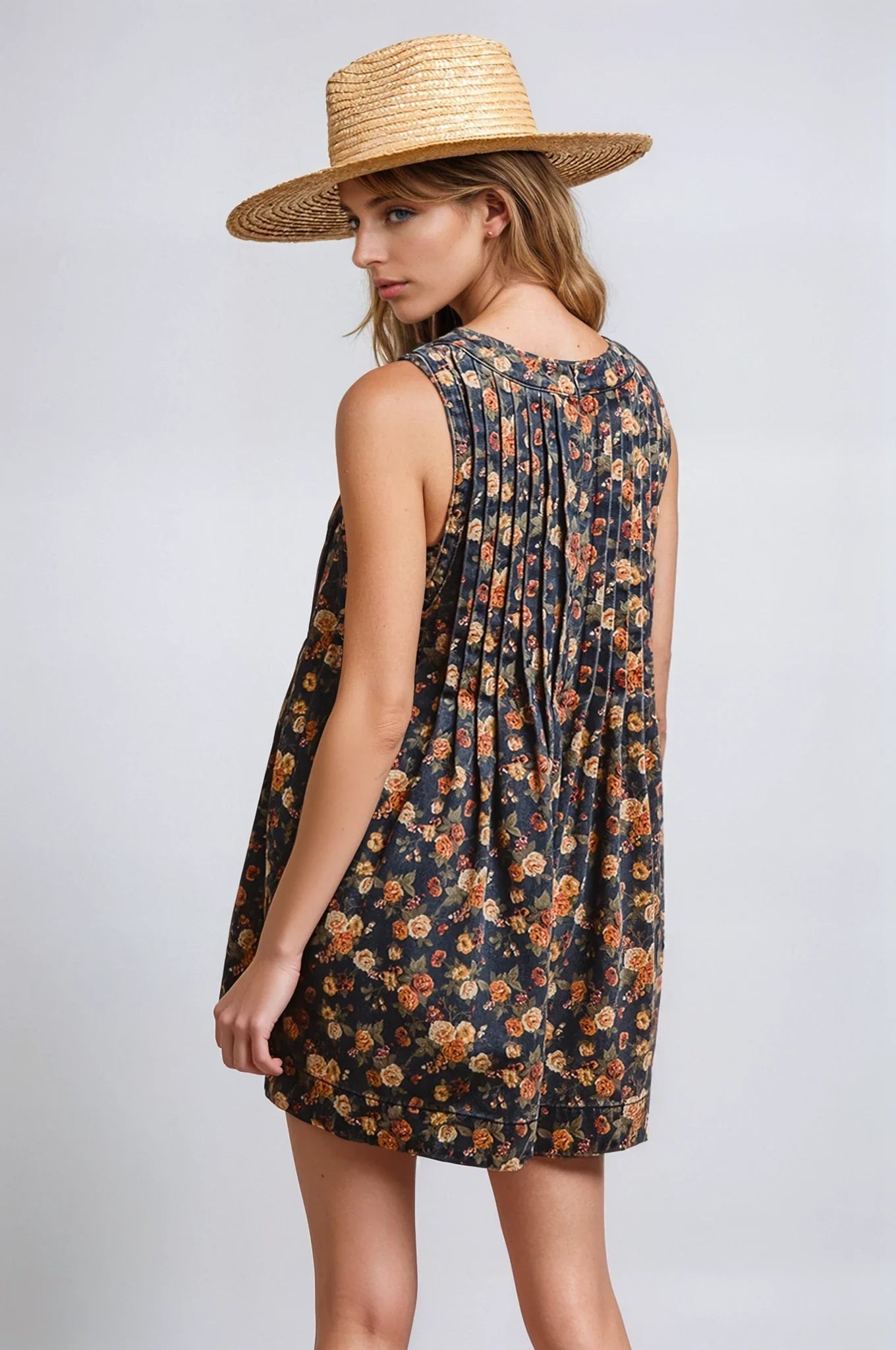 Woman wearing a floral dress and straw hat on a plain background