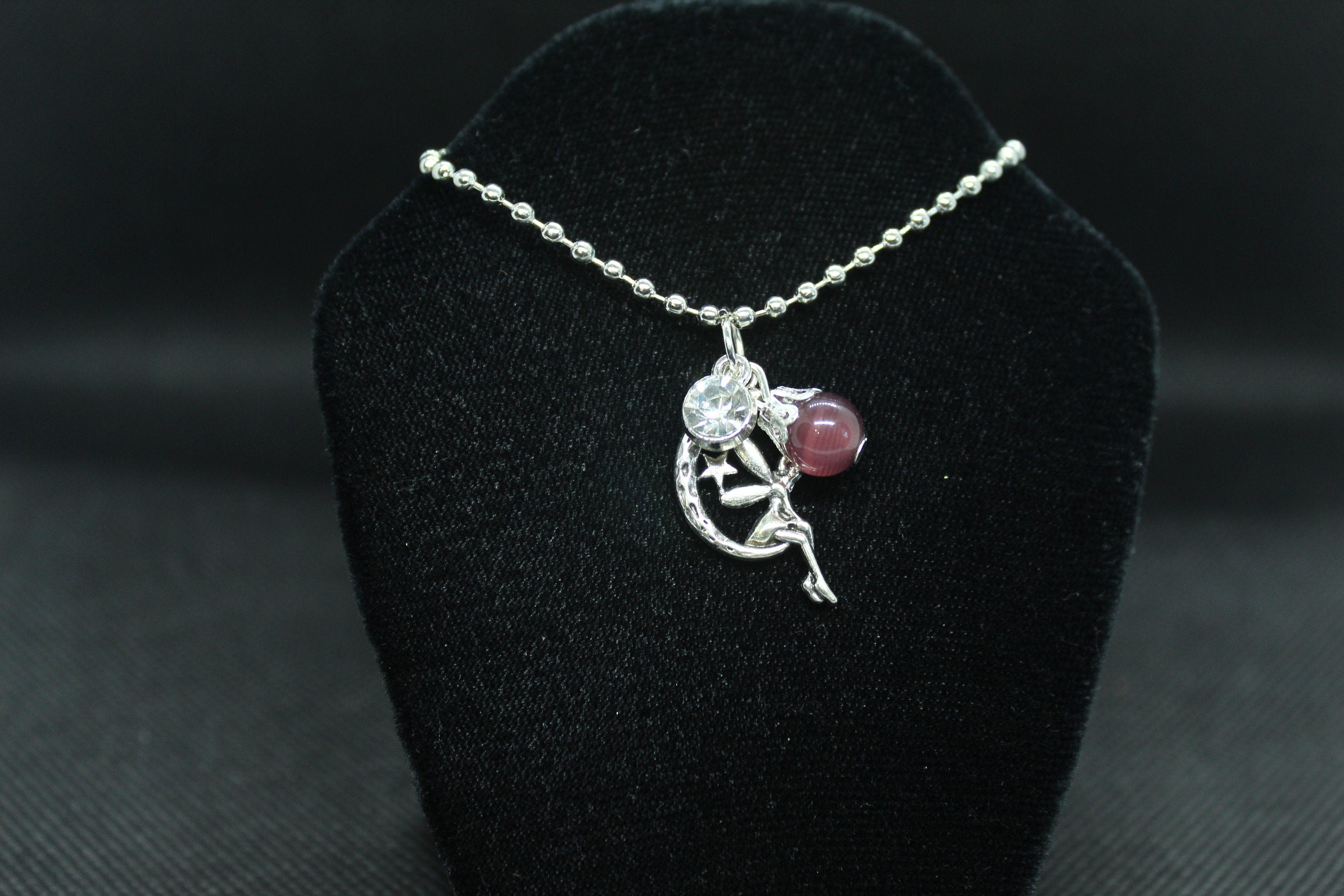 silver necklace with pendant on a black velvet stand