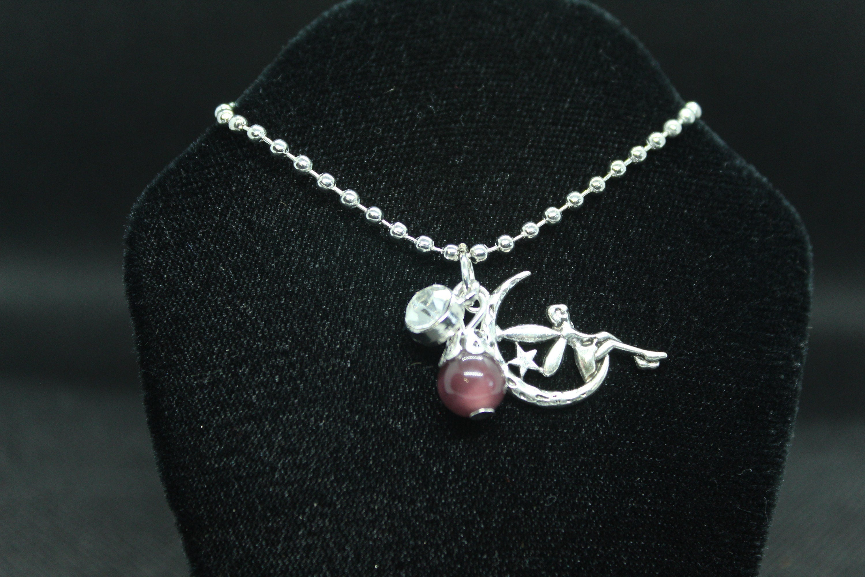 silver necklace with pendant on a black velvet stand