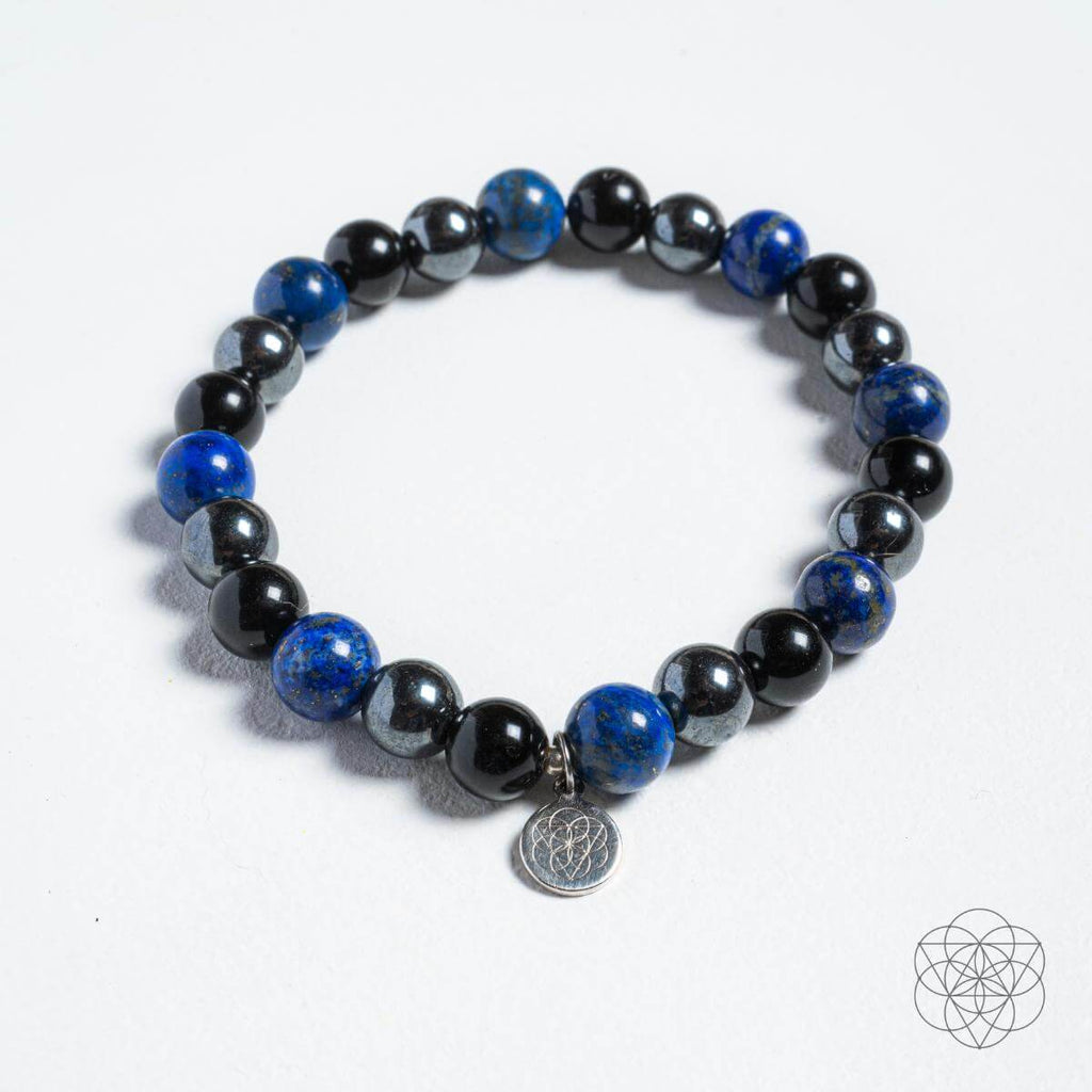 Black and blue beaded bracelet with a silver charm on a white background