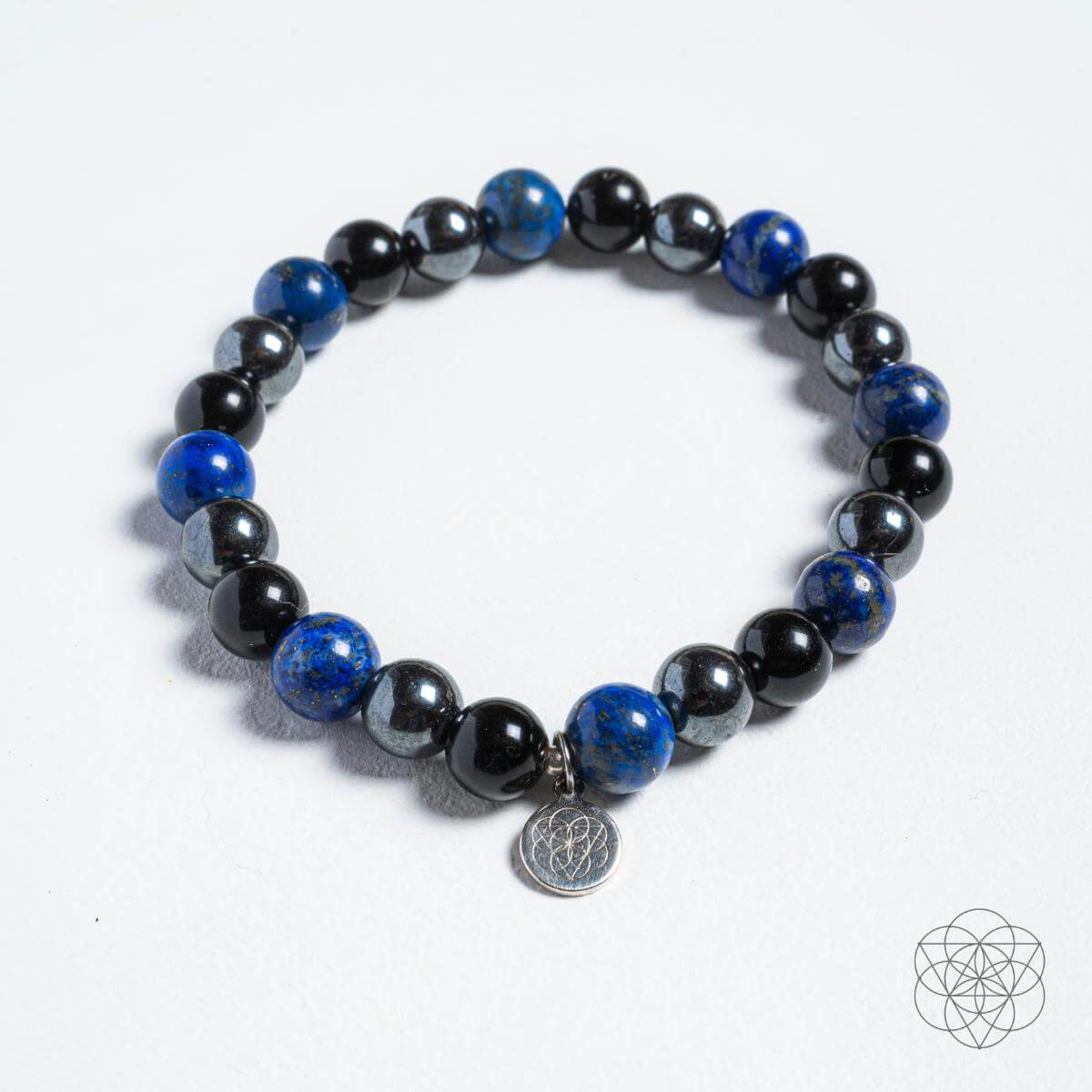 Black and blue beaded bracelet with a silver charm on a white background