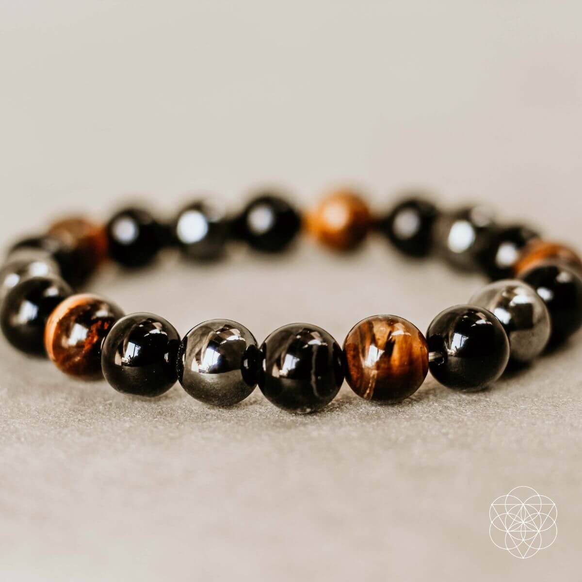 Bracelet with black, brown, and gray beads on a neutral background